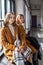 Mom and teenage daughter in yellow clothes relax by the window .Parents and teens. Family look