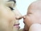 Mom touches her nose on the nose of a sleeping newborn baby close-up