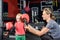 Mom the trainer helps the little girl put on boxing gloves
