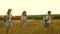 Mom travels with her daughters. Mother and children are tourists. Girls travel across field in sunset light. Hiker girl