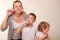 Mom and two blond boys brush their teeth