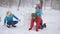 Mom and two daughters together mold made of snow snowman. Winter family games outdoors.