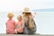 Mom and two sons sit on the pier and admire the sea and the mountains in the distance. Back view