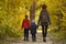 Mom and two sons walking in the autumn forest. Back view