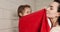 Mom wipes her daughter with a red towel and hugs her in the bathroom. Mother\'s hugs.