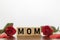 MOM word written on wooden cubes with red roses and hearts around