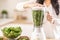 The moment before green leaves become smoothie as woman holds blender full of spinach