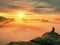 Moment of loneliness on exposed rocky summit. Man in black enjoy marvelous view. Hiker sit on the peak