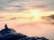 Moment of loneliness on exposed rocky summit. Man in black enjoy marvelous view. Hiker sit on the peak