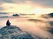 Moment of loneliness on exposed rocky summit. Man in black enjoy marvelous view. Hiker sit on the peak