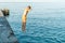 Moment of schoolboy jumping from pier into sea doing tricks