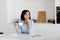 Moments of relax. Dreamy lady drinking coffee and looking away, sitting in kitchen interior, free space