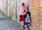 Mommy and child posing and leaning on an old brick wall wearing jacket during cold weather