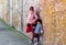 Mommy and child posing and leaning on an old brick wall wearing jacket during cold weather