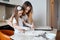 Mommy teaching her daughter to draw a heart on the table with spilled flour