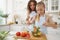 Mommy teaching her teen daughter to cook vegetable salad in kitchen