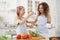 Mommy teaching her teen daughter to cook vegetable salad in kitchen