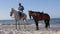 Monastir, Tunisia - 08 June 2018: mar rider sitting astride horse and taking cigarettes while walking on sandy beach at