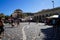 Monastiraki square on sunshine day with people activities, market, pigeon and view of the Acropolis through old town buildings