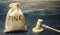 Money bag with the word Fine and the judge`s hammer. Penalty as a punishment for a crime and offense. Financial punishment.