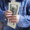 Money is the best motivation. A child holding dollars banknotes.