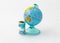 A money box made in the form of a globe, the planet Earth with a money slot at the top stands near a rolled up and held together s