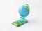 A money box made in the form of a globe, the planet Earth with a money slot at the top stands on a stack of Israeli banknotes of d