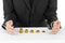 Money and business theme: a man in a black suit indicates the chart bars of gold coins on a white table in the studio on a white b