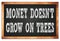 MONEY DOESN`T GROW ON TREES words on black wooden frame school blackboard