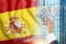 Money in a man`s hand against the background of the flag of Spain. The income of the Spaniards. The financial condition of