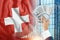 Money in a man`s hand against the background of the flag of Switzerland. Swiss income. The financial condition of residents of