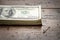 A money pile of stacked one hundred US banknotes with president Franklin portrait over wooden table background.