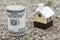 Money roll with small toy house on background. Real estate price concept. Selective focus