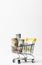 Money rolled up in a tube in a cart on a white background. Copy space. Close-up. Sales and shopping concept. Vertical