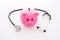 Money for treatment. Medical expenses. Moneybox in shape of pig near stethoscope on white background