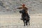 Mongolia. Traditional Golden Eagle Festival. Unknown Mongolian Hunter Berkutchi On Horse With Golden Eagle. Falconry In West M