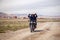 Mongolia Ulgii 2019-05-04 Mongolian men ride motorbike at steppe field on village background ang send greetings. Concept