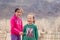 Mongolia Ulgii 2019-05-05 Two smiling Mongolian girls in colorful clothes on background of fence, mountains. Concept of