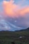 Mongolian landscape with mountain steppe under running cumulus clouds on sunset sky, yurts and goats herd