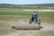Mongolian man rolls felt in steppe with a small tractor in Harhorin, Mongolia.