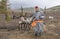 Mongolian man in a traditional deel walking with reindeers