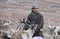 Mongolian man in a traditional deel walking with reindeers