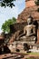A monk meditating in front of buddhas statue large in SUKHOTHAI