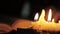 Monk reading and touching a yellow pages of old book. Close-up candle light.