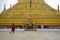 A monk in red robe passing by the main stupa of Shwemawdaw Pagoda