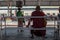 A monk waiting on a bench by the Yangon circular train station, Myanmar