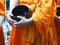 Monk wear yellow robe holding black alms bowl for food offering in morning