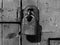 monochrome close up of an old rusty closed padlock and hasp on a distressed wooden plank door