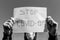 Monochrome image of a desperate teenage boy wearing surgical mask holding a message in isolation