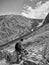 Monochrome image lone traveler with a backpack sitting on a rock and looking at the snowy mountains